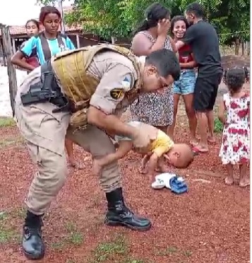  Momento em que o policial militar realizava a manobra para desengasgar a criança. - Foto: Divulgação